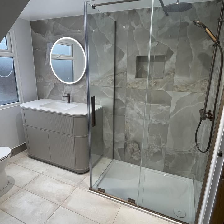 Walk-in shower with onyx effect tiles beside a curved fluted vanity