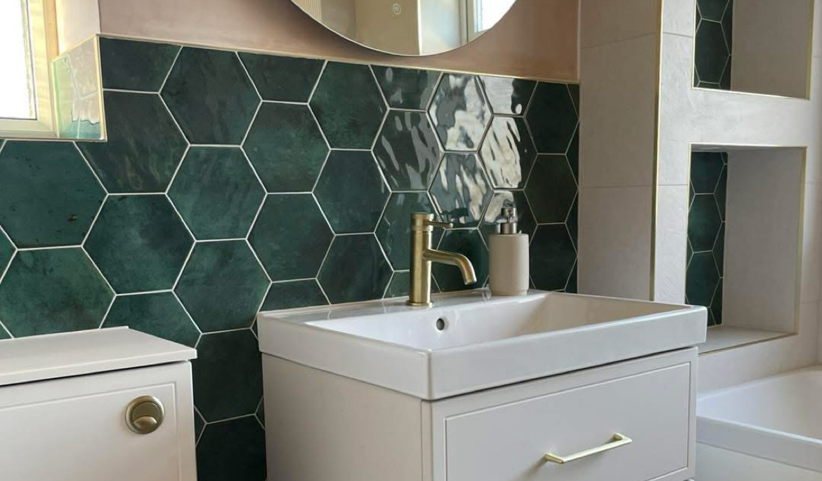 Green hexagon tiles above a white vanity with a brass tap