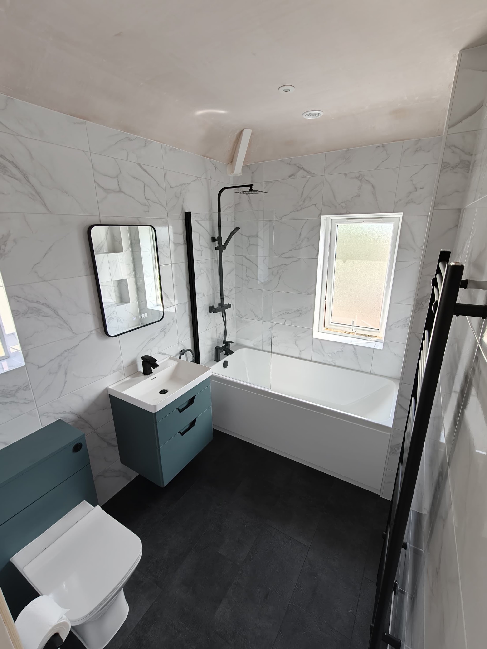 Marble effect bathroom with a teal vanity unit and black fittings