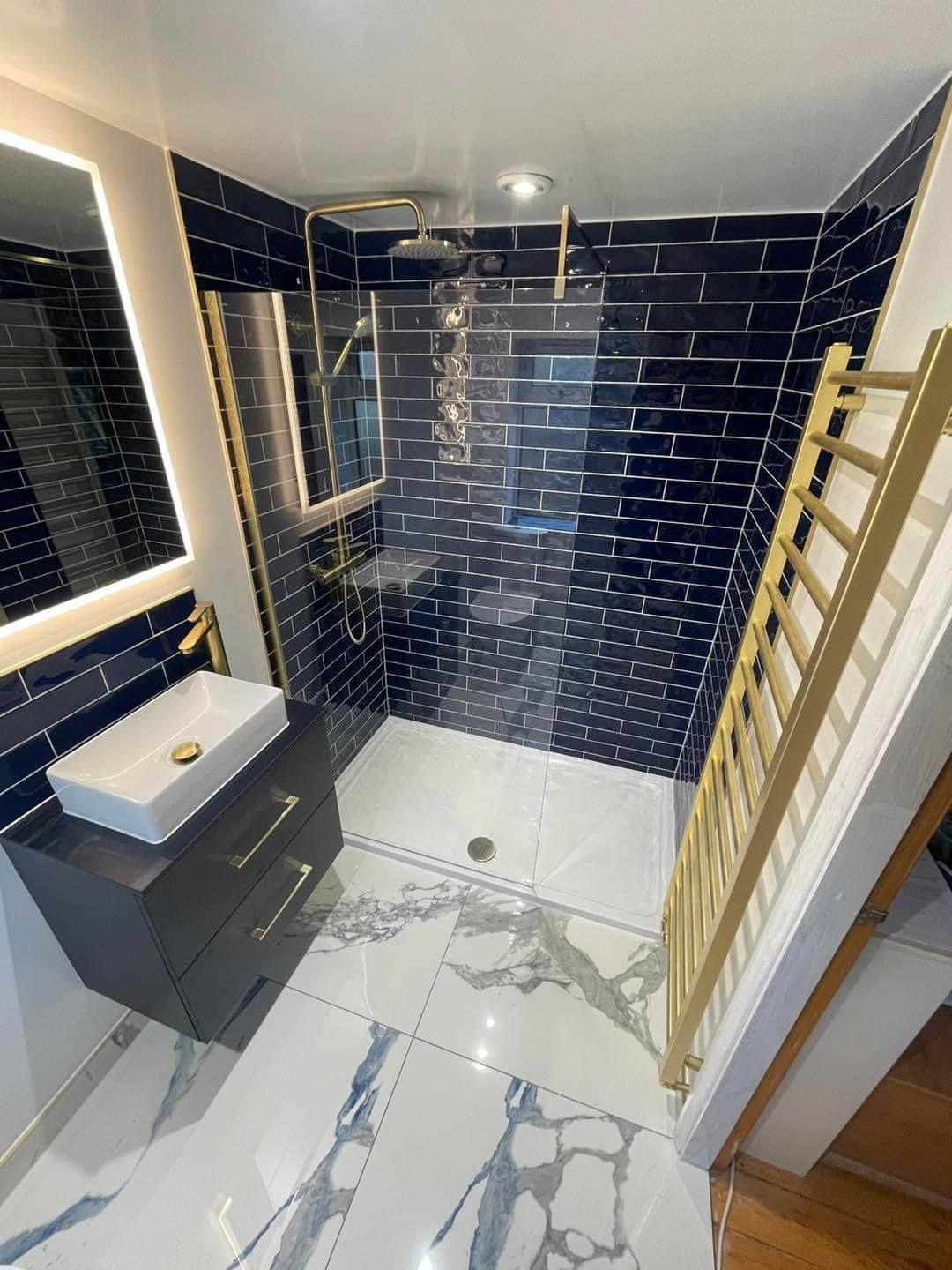 Navy metro tiled shower room with brass fittings and a marble floor
