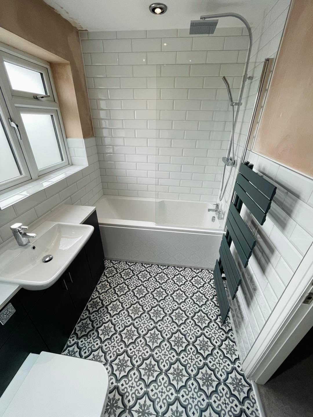 White metro tiled bathroom with patterned floor tiles and shower over the bath